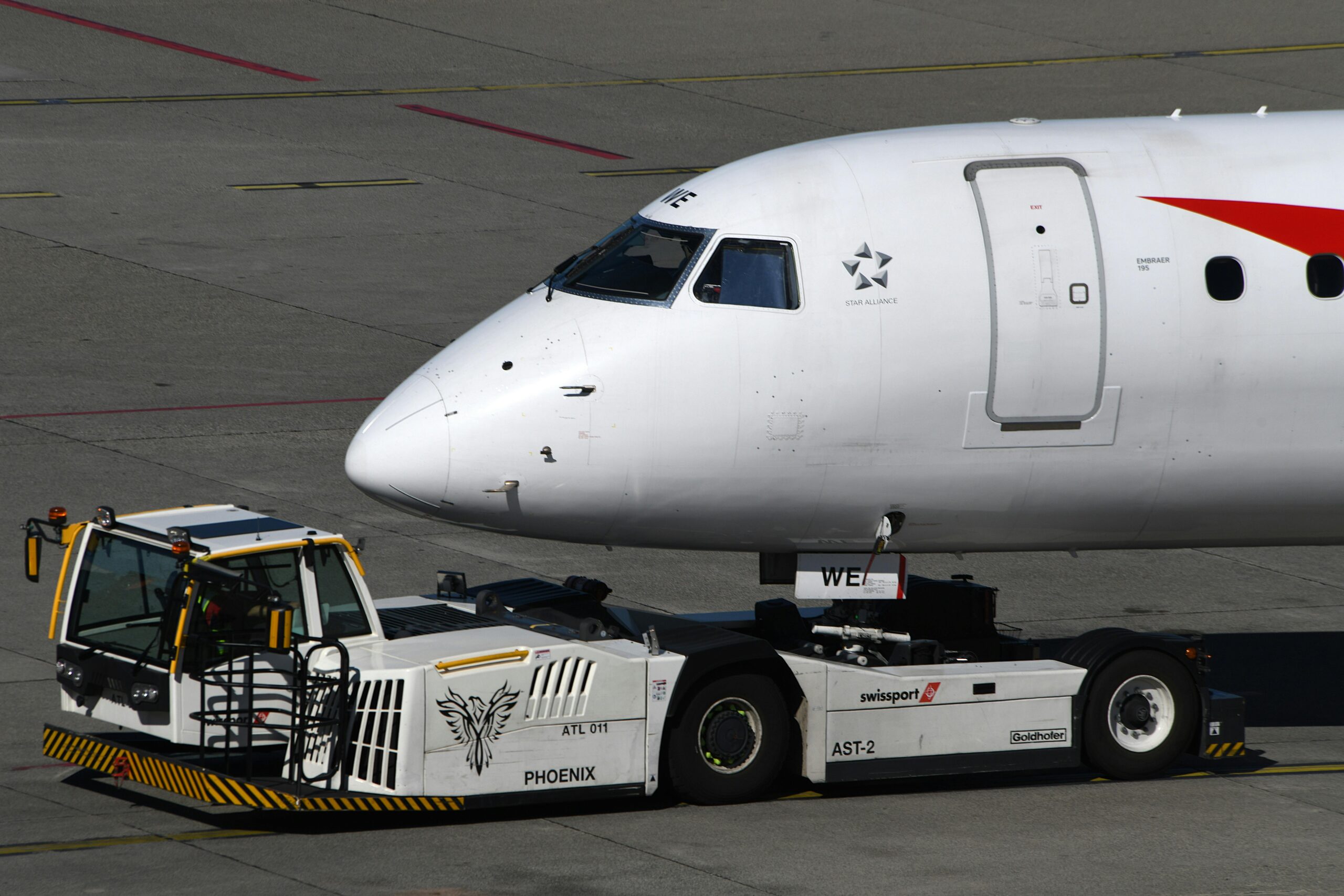 Towbarless aircraft pushback tractor towing Embraer jet at airport apron